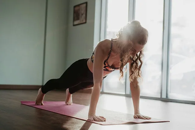 Mujer haciendo plancha sobre una esterilla junto a la ventana